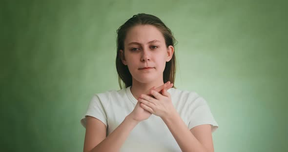 Upset Young Woman Wipes Tears By Fingers on Green Background
