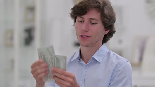 Portrait of Successful Young Businessman Counting Dollars