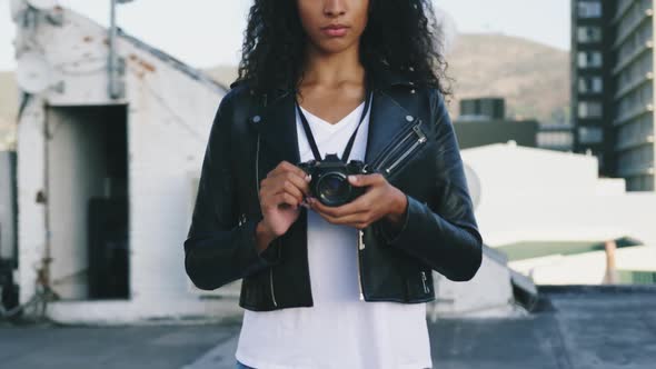 Fashionable young woman on urban rooftop holding a camera