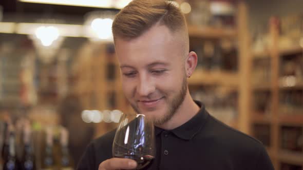 Male Visitor To a Liquor Store Takes the Offered Wine Glass and Sniffs the Aroma of the Wine