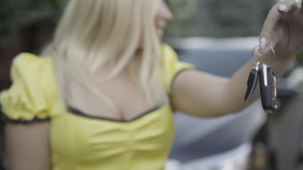 Close-up of Slim Female Caucasian Hand Holding Car Keys with Blurred Smiling Blond Woman Looking