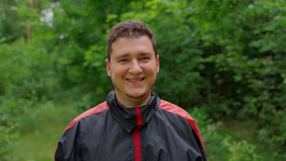 Happy man looking at camera smile laughing at forest. Attractive 30s young adult person customer