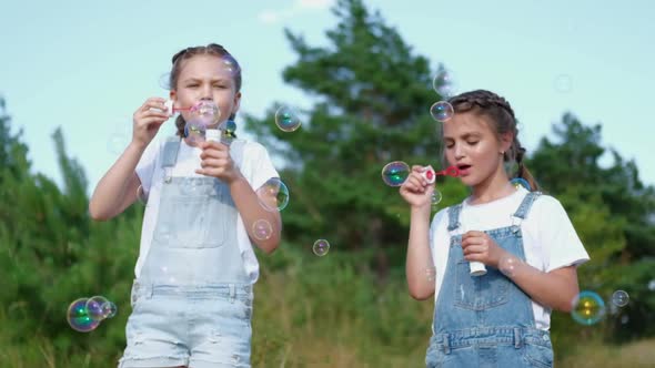 Two Little Girls Blowing Soap Bubbles in the Park