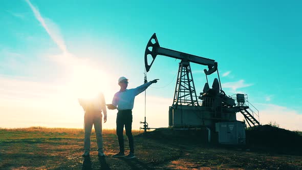 Oil and Gas Industry Concept. Male Power Workers Are Observing an Oil Pumping Site