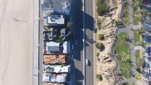 Birds eye view of traffic driving in city beach, shot on drone panning sideways looking directly dow