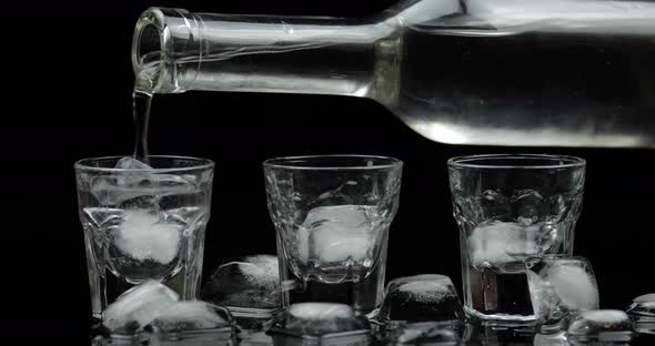 Pouring Up Three Shots of Vodka From a Bottle Into Glass. Black Background