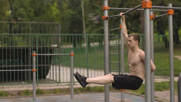 Strong Shirtless Caucasian Athlete Performing Corner on Horizontal Bar