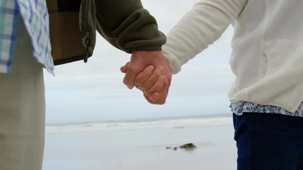 Mid section of old caucasian couple walking hand in hand at beach 4k