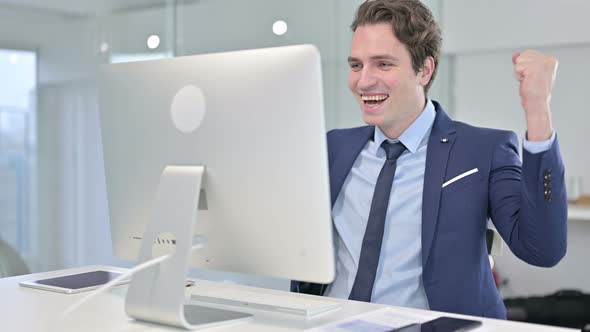 Ambitious Businessman Celebrating Success on Desk Top 