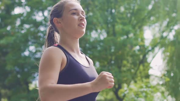 Low Angle Shot Woman Runner in Park Slow Motion, Female Runner Smiles, Training