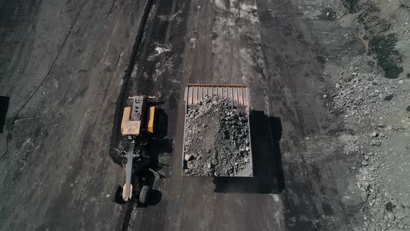 Grader Lays New Road in Quarry Next to Overweight Dump Truck Carrying Coal