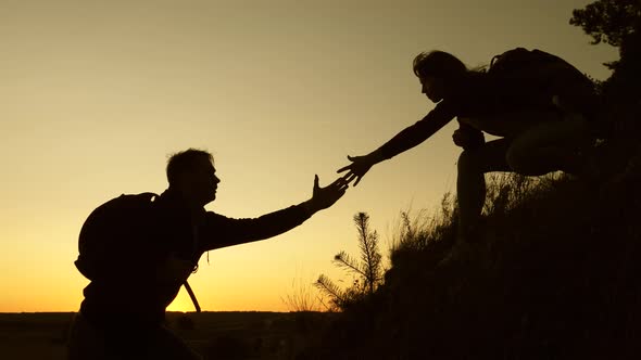 Traveler Woman and Man Hold Out Their Hand To Each Other Helping To Climb the Mountain, Tourists