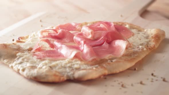 Camera follows putting fresh arugula leaves on a white pizza. Slow Motion.