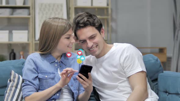 Smiling Young Couple Using Smartphone Flying Smileys Emojis and Likes