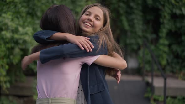 Charming Teenage Girl Meeting Friend in Park Hugging Smiling Looking Away