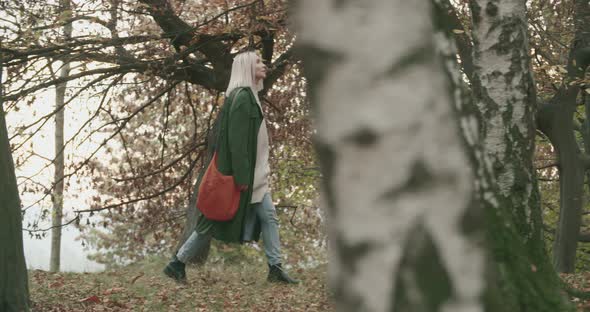 Side View of Young Woman Walking Alone in a Forest or in a Park To Restore Herself, Playing with