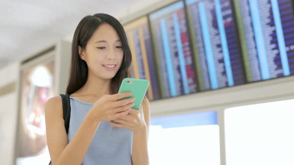 Woman use cellphone to check the flight number in airport 