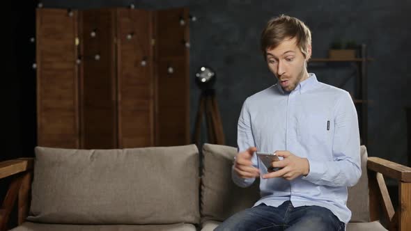 Happy excited young man using smart phone and celebrating success