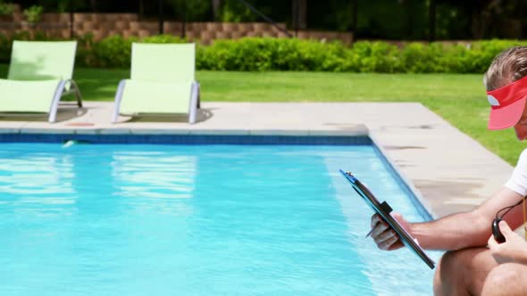 Lifeguard holding clipboard and looking at stop watch