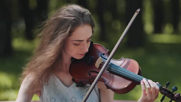 A Young Girl Plays the Violin in the City Park