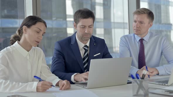 Business People Sharing Report Through Laptop and Making Documents on Office Table