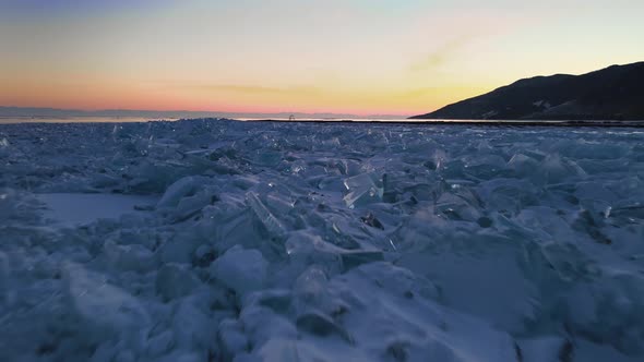 Flying over the ice hummocks. Blocks of cracked broken ice glisten at sunset