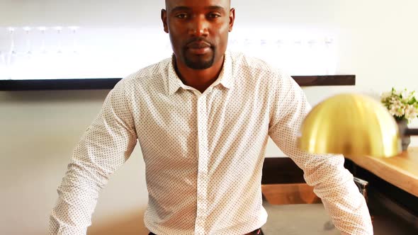 Portrait of man standing with arms crossed in restaurant