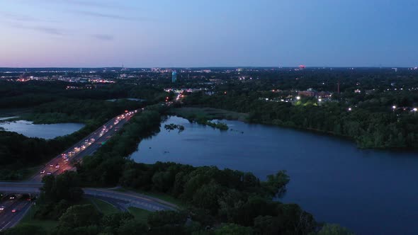 a slow aerial drone flight towards a lake with traffic on the highway on the left, then a slow tilt