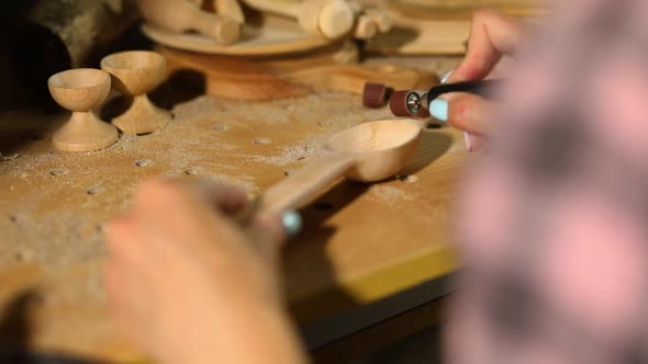 Female using power working tools graver for wooden utensils spoon, carving
