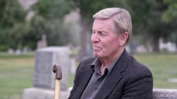 Elderly man sitting at cemetery