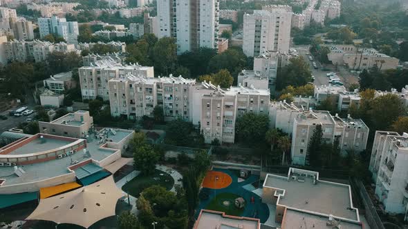 Aerial Tracking Past Sunlit Houses on Hilltop at Sunrise in Haifa Israel