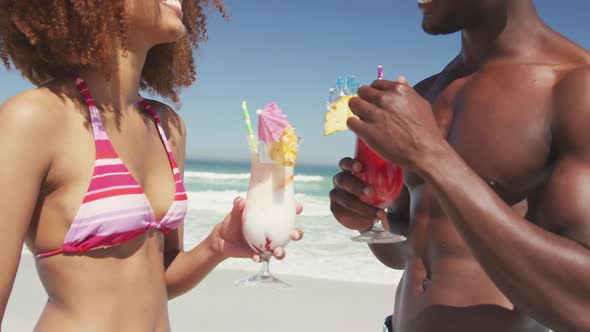 African american couple drinking cocktail seaside