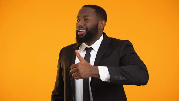 Funny African-American Male in Suit Making Thumbs-Up and Winking Service Quality