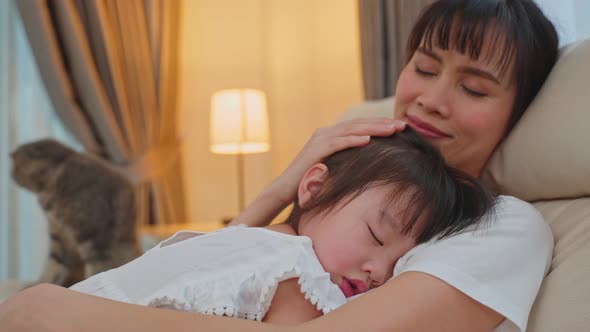 Asian beautiful loving mother hugging sleeping baby girl in her arms with gently.