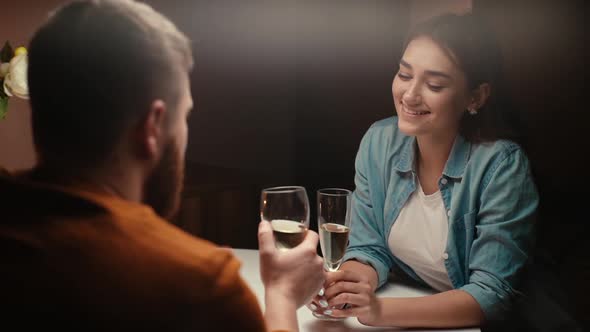 Back View of Happy Couple of Clinking White Wine Glasses or Champagne During Romantic Dinner