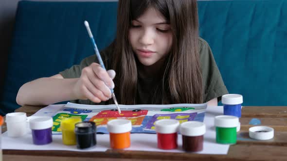 Little Girl Sits at the Table and Draws a Gouache Drawing