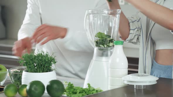 Vegetarianism Young Couple Prepares a Smoothies in the Kitchen Man and Woman Puts the Green