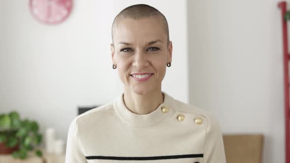 Mid Adult Woman with Shaved Head Smiling at Camera While Standing at Home