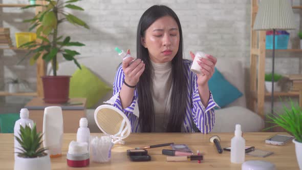Portrait of an Asian Young Woman Thoughtfully Choosing Cosmetics
