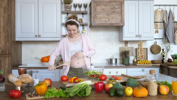 Happy Pregnancy Concept. Cheerful Pregnant Girl Dancing And Singing In Kitchen.