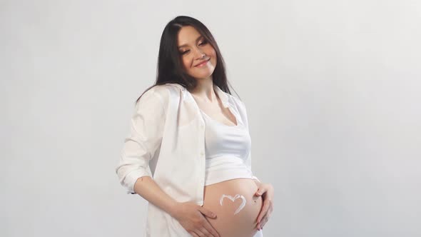Pregnant Woman Posing with Hands on Naked Belly Over Purple Wall