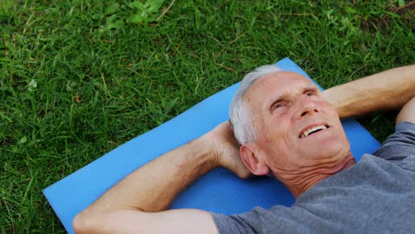 Senior man lying on exercise mat in garden 4k