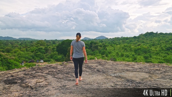 4K Woman Walking Towards Forest Clearing with Panorama View of the Jungle and Sky