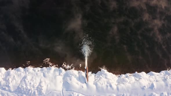 Top-down View Of Drain Pipe With Water Running Out On Lake During Winter In Frydman, Poland. - aeria