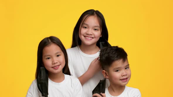 Asian Kids Taking Off Face Mask Smiling Over Yellow Background