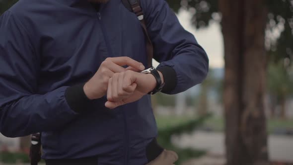 Man Is Controlling His Smartwatch Closeup of His Hands Outdoors