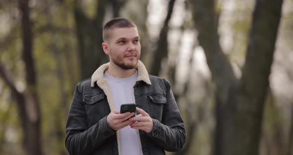 Slow Motion Smiling Man Use Smartphone Walking in the Park