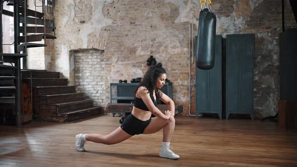 African American Woman Does Forward Lunge Exercise in Gym