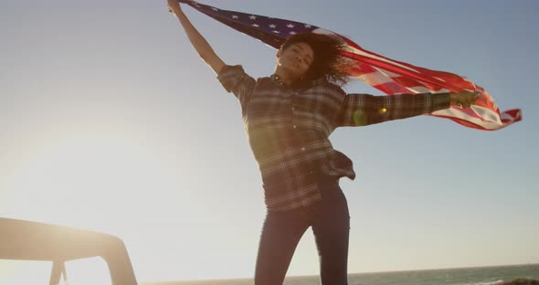 Woman waving american flag on pickup truck at beach 4k