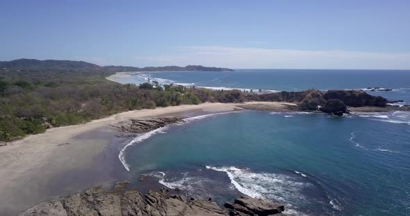 Aerial drone view of the beach, rocks and tide pools in Playa Palada, Guiones, Nosara, Costa Rica.